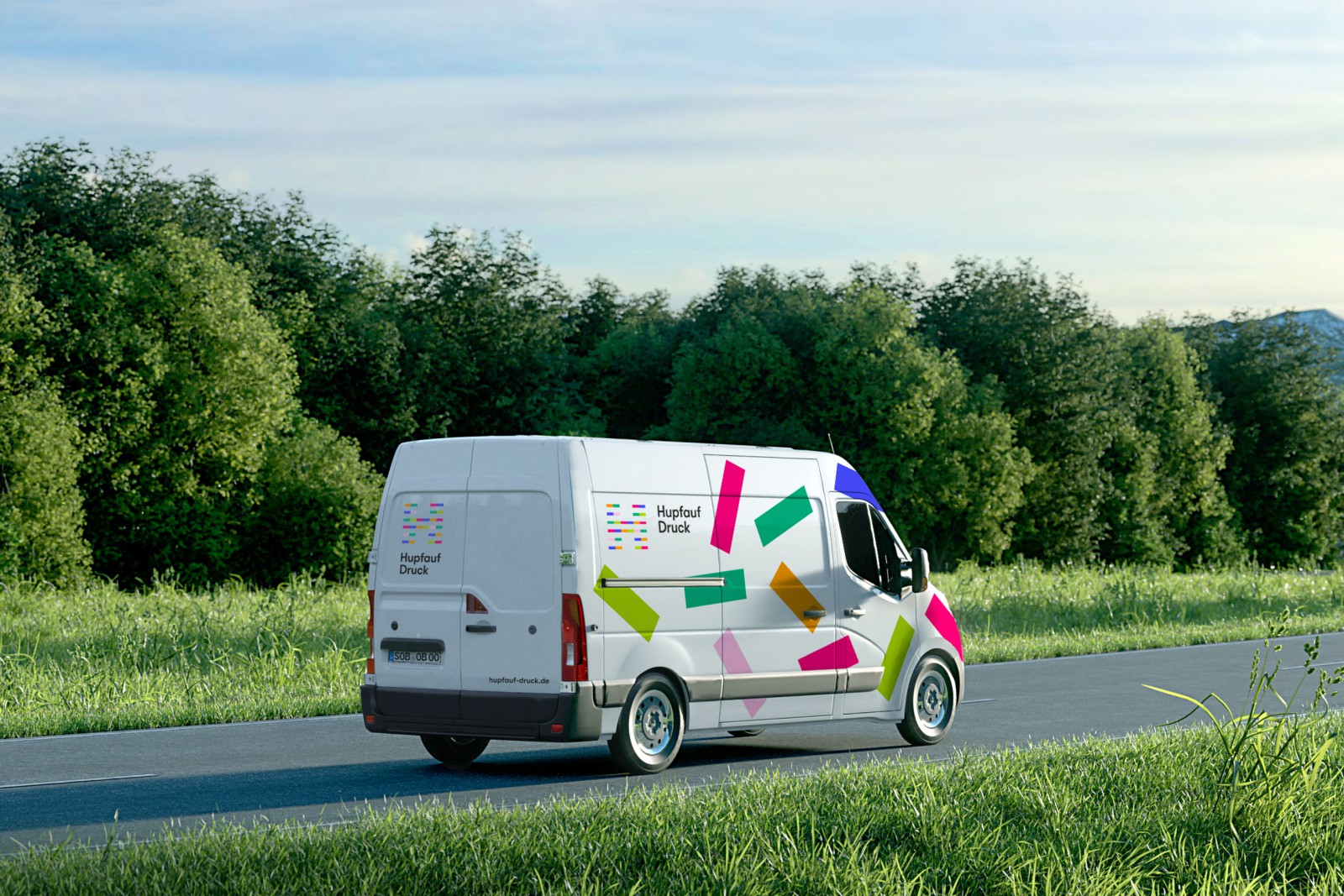 A white delivery van with colorful &ldquo;Hupfauf&rdquo; branding on a country road in front of green trees