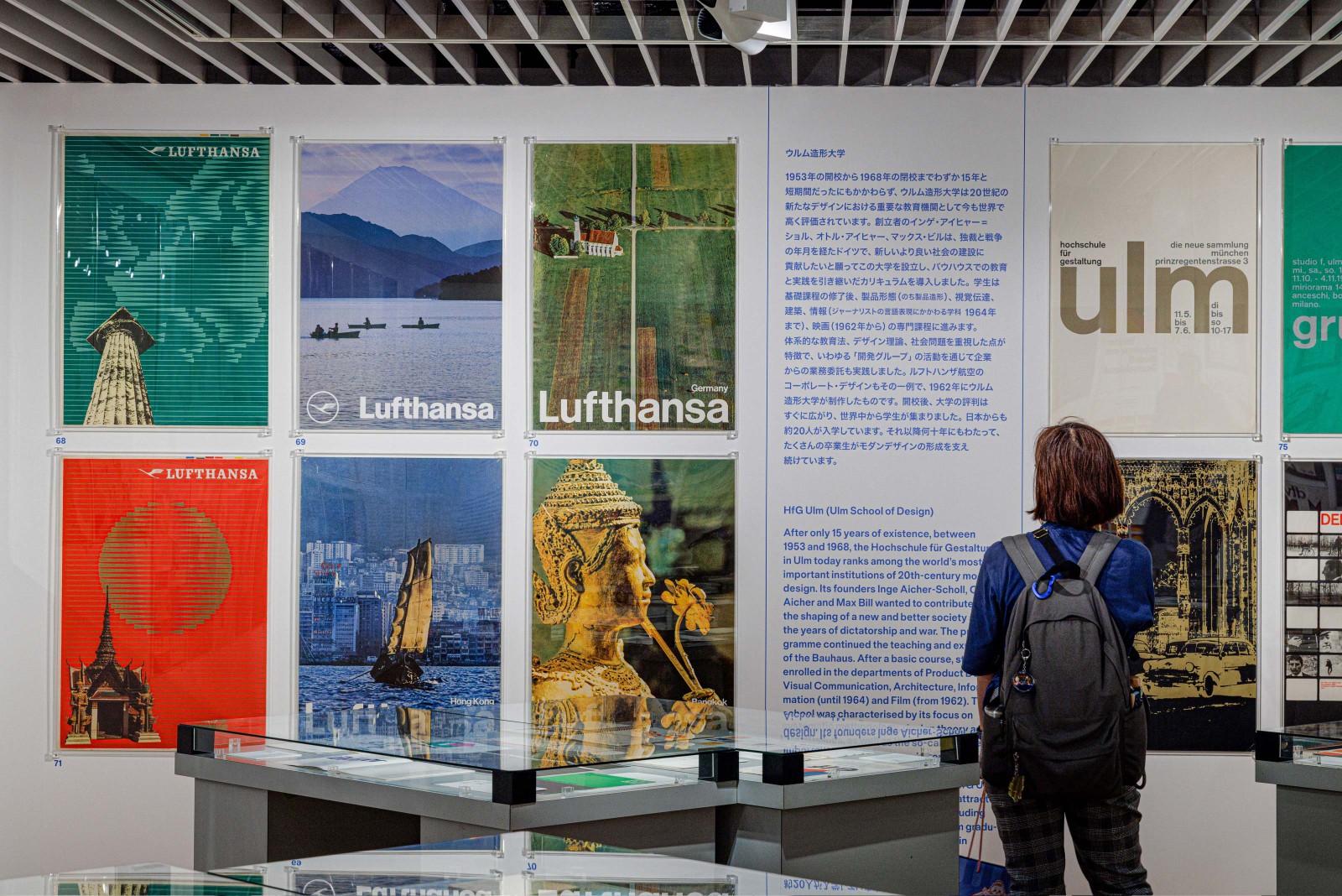 Ausstellungswand mit historischen Lufthansa-Reiseplakaten und Plakaten der HfG Ulm (Hochschule für Gestaltung, Ulm) mit Besucherin