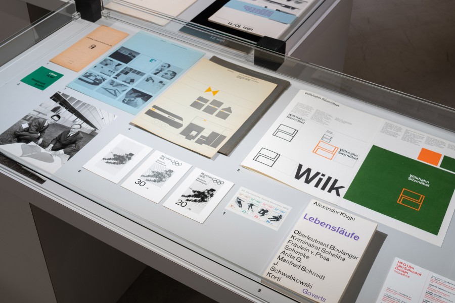 Glasvitrine mit Corporate-Design-Handbüchern und Erscheinungsbildern, darunter Wilkhahn Sitzmöbel, clima Hotel Innsbruck, die Olympischen Spiele München 1972 und die HfG Ulm