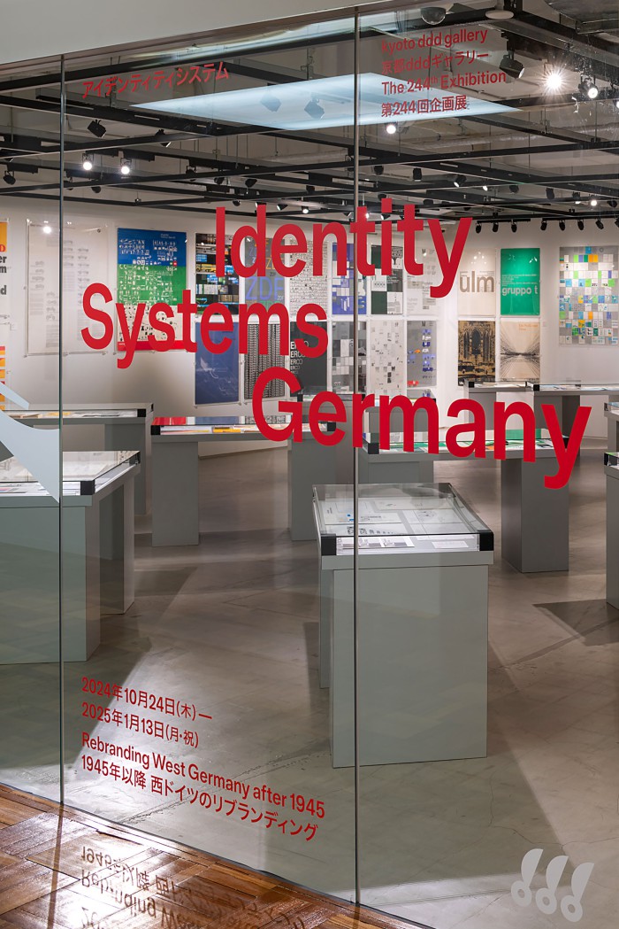 Einblick in die Ausstellung mit Fentsterbeschriftung in die Kyoto ddd Gallery mit rotem Schriftzug „Identity Systems Germany – Rebranding West Germany after 1945“