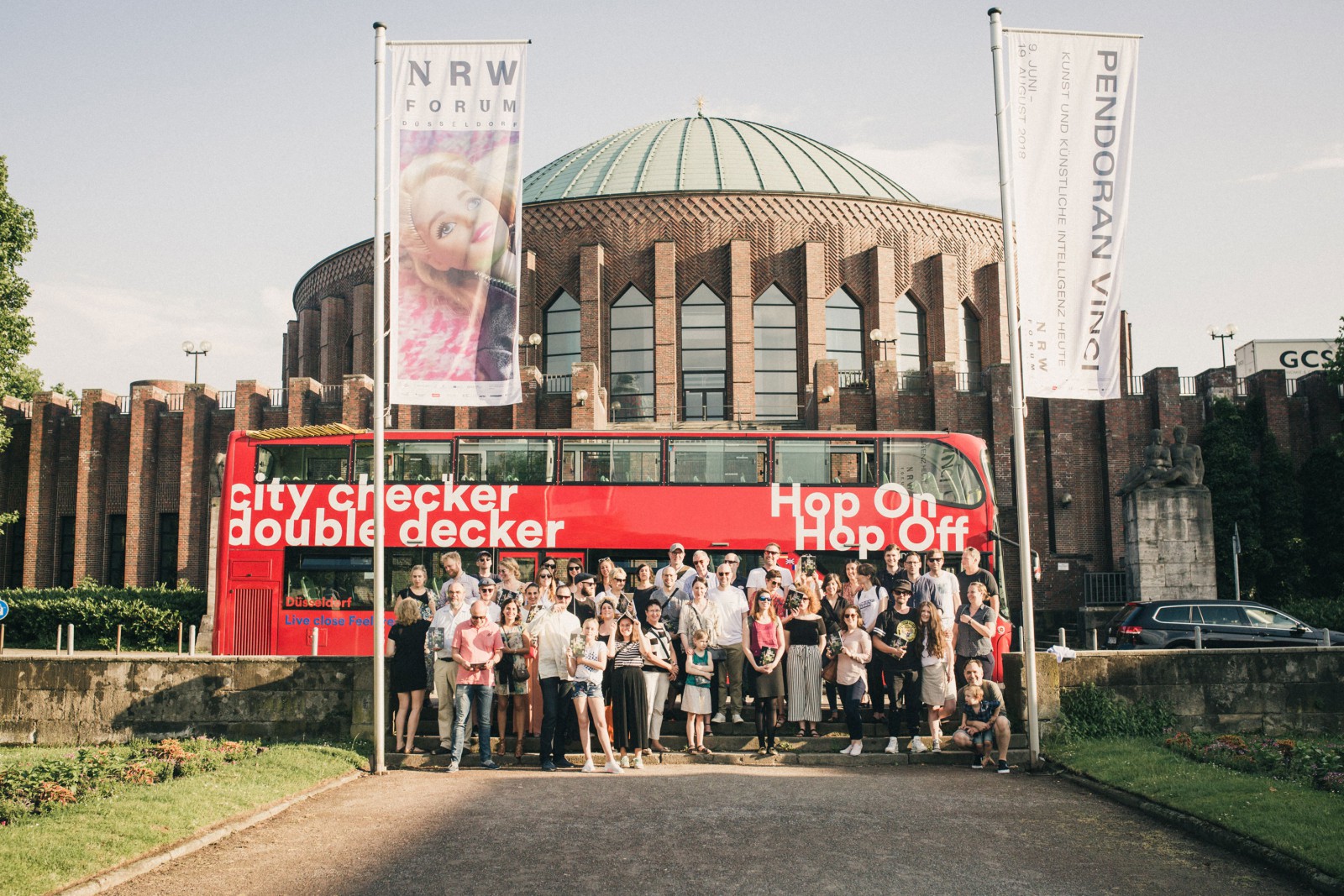 Gruppe vor dem NRW Forum - der Tonhalle in Düsseldorf mit rotem Doppeldeckerbus „City Checker Double Decker“ anlässlich der Release Party THE DORF THE MAG No. 2